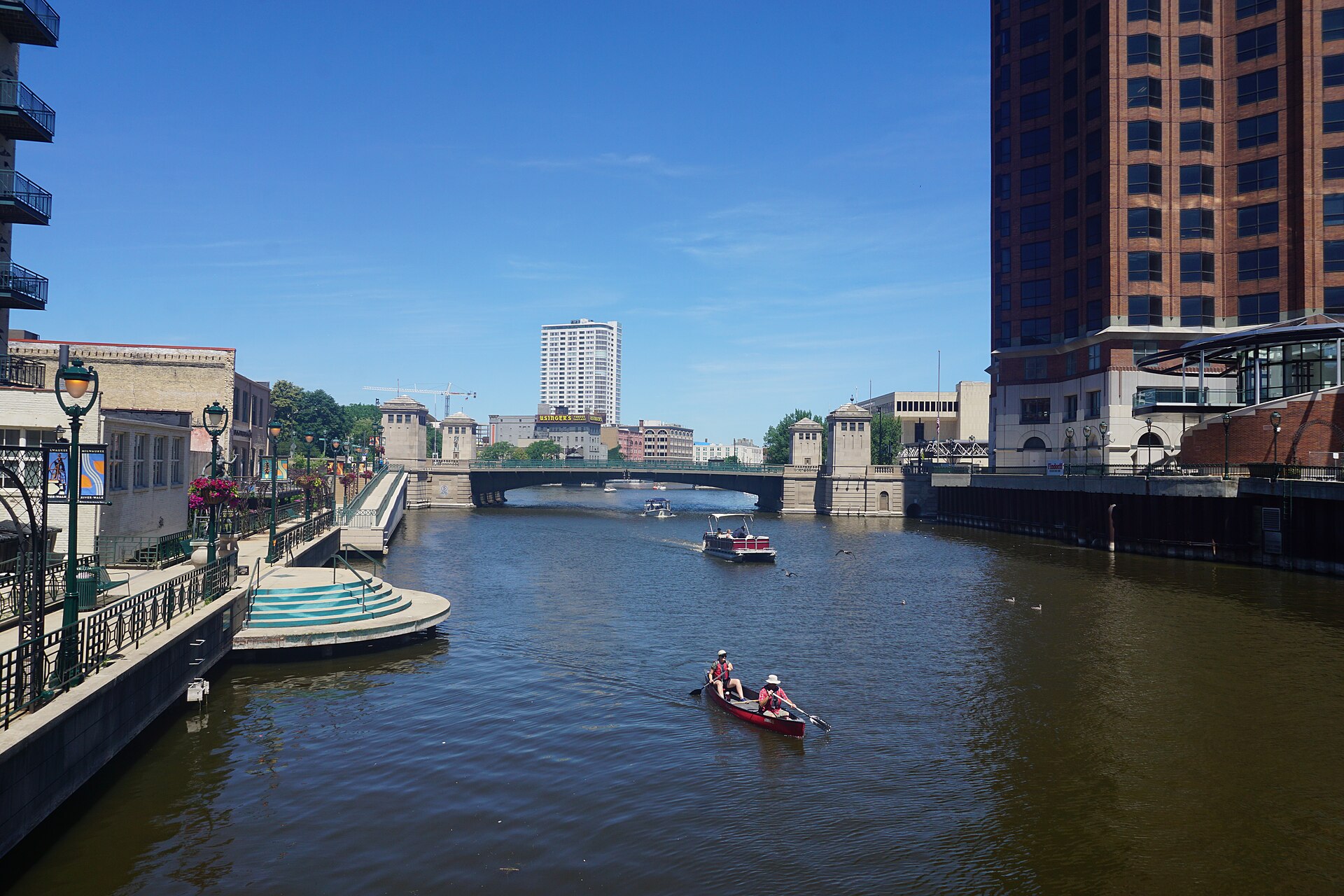 The Milwaukee Riverwalk lit at dusk with bridges and downtown towers